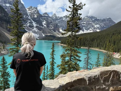 Kvinna i TourCompass-t-shirt blickar ut över vattnet vid Lake Louise i Kanada