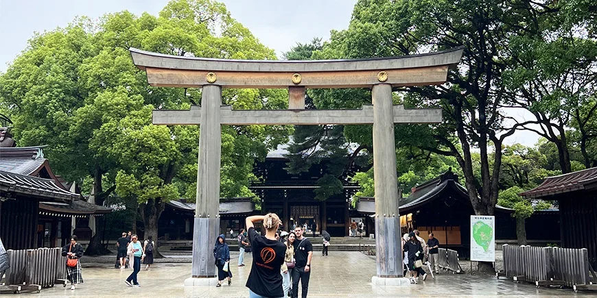 Kvinna tar bild av par under en torii-port vid Meiji-helgedomen