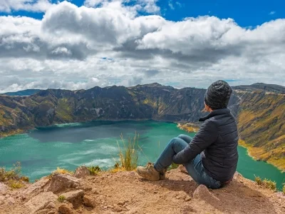 En kvinna sitter vid kanten av kratersjön Quilotoa i Ecuador.