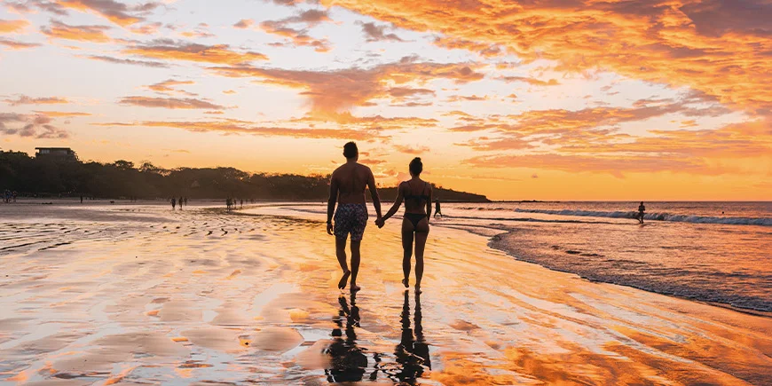 Man och kvinna promenerar på Tamarindo Beach i Costa Rica
