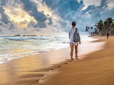 En kvinna går på stranden på Sri Lanka
