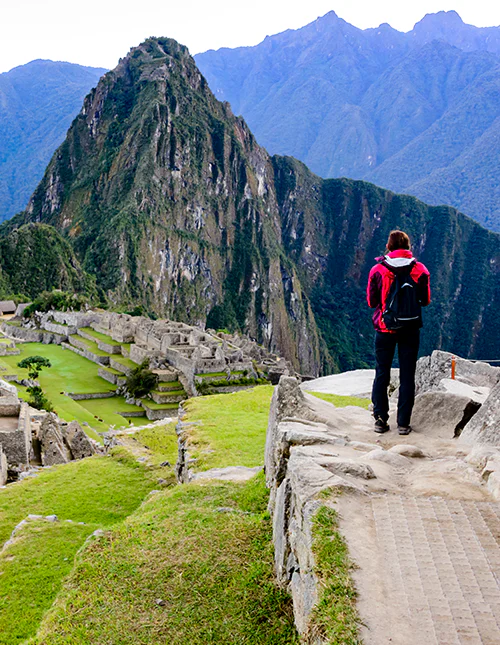 En person står och blickar ut över Machu Picchu